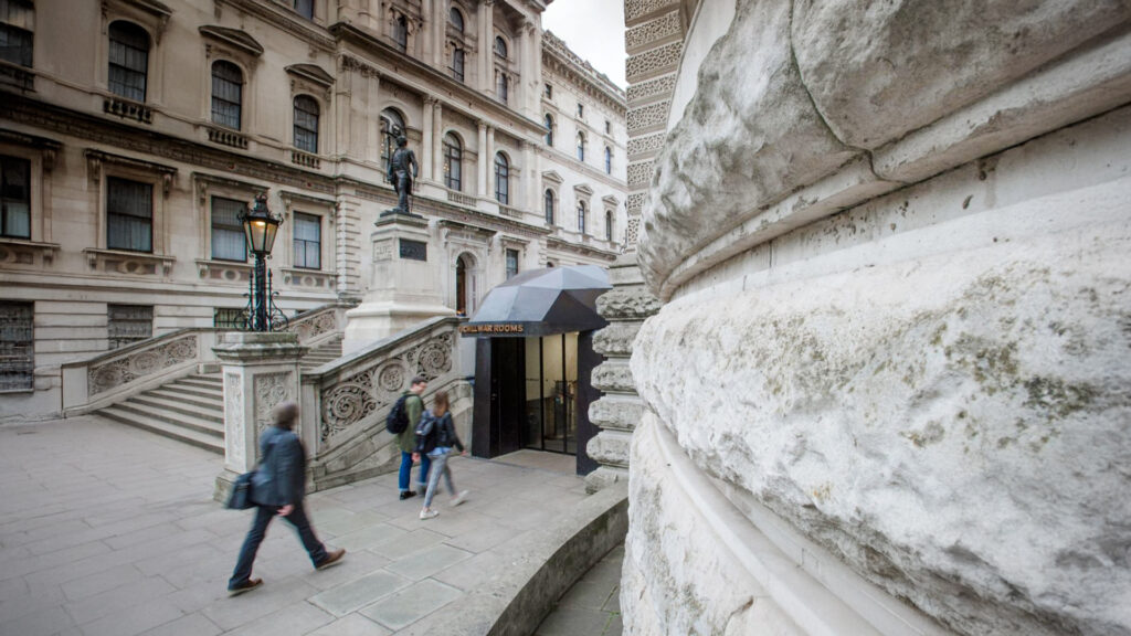 People walking near the entrance of a building with a tent